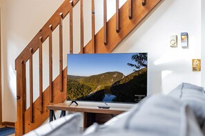 Cozy living room with a comfy couch and loveseat, perfect for relaxing after a day of adventure. Enjoy the warmth of the decorative propane fireplace and stream your favorite shows on the Smart TV for a perfect night in!