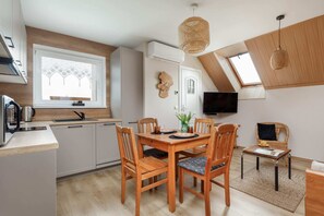 A wide-angle view of the dining and living area, showing a wooden dining table, chairs, and a comfortable sofa.