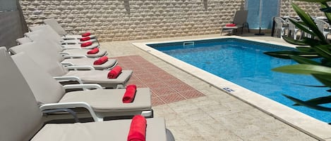 Pool and sun louge area, with outdoor dining table and chairs , and shower