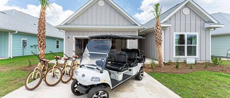 Front of home with six seater golf cart, four bicycles and two paddle boards.