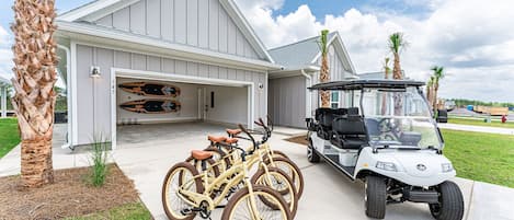 Front of home with six seater golf cart, four bicycles and two paddle boards.