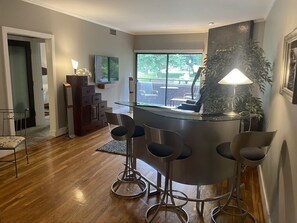 Living room with bar area, flat panel tv, surround sound speakers.