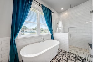 Soaking tub with Glass covered shower featuring two shower heads. One being rainfall.