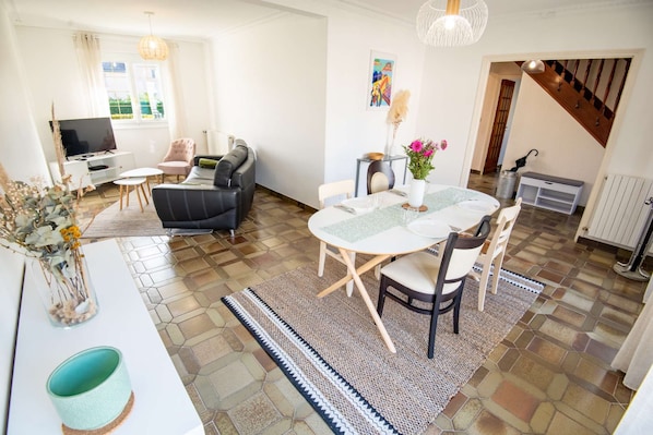 Belle pièce de vie avec coin salon et coin repas ouvrant sur un balcon donnant à l'avant de la maison