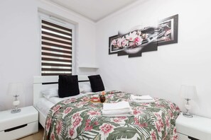 A bedroom with a comfortable double bed, floral bedding, bedside lamps, and stylish decor elements such as floral artwork on the wall.