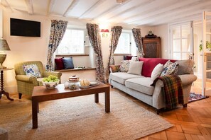 The Craftsman's Cottage - sitting room with large sofa, two single armchairs and two window seats