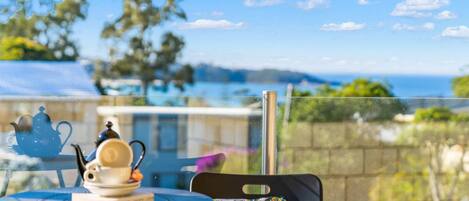 Elevated front deck balcony with sun lounges and views across to Mollymook beach.