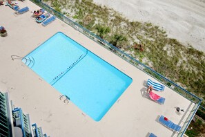 Beautiful 4th floor oceanfront pool with tables and lounging area.