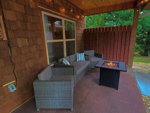 The private front patio features comfy seating, fire pit table & party lights.