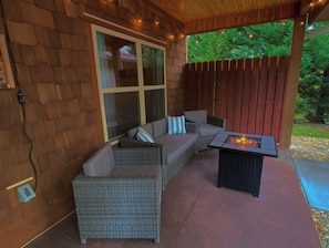 The private front patio features comfy seating, fire pit table & party lights.