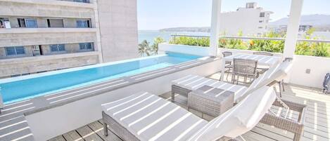 Rooftop with loungers, pool, and ocean views