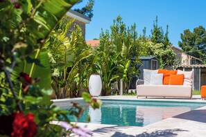 La piscine chauffée et son salon de jardin coloré avec une enceinte bluetooth
