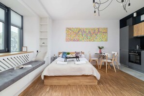 An open-plan studio with a comfortable bed, a dining area, and a kitchenette, blending functionality and style.
