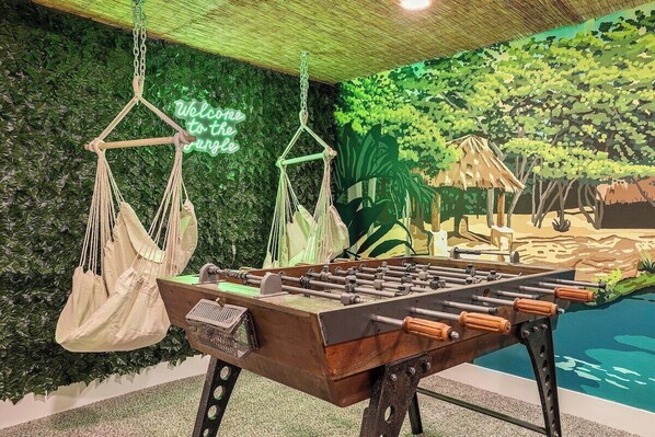 The backdrop of this lounge / game room would make you feel like you're in an exotic place but with the modernity of the provided hammocks and foosball.