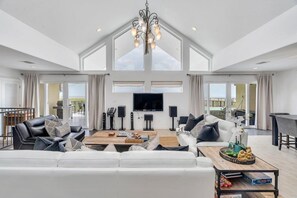 Living room featuring two large sofas, a chaise, dining for 10 at the table, and a full service wet bar.
