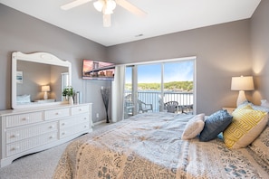 Perfect blend of nature and modern design in the master bedroom boasting a queen bed, a smart TV, and stunning lake views.