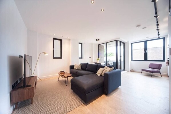 Spacious open living area with a connected kitchen, a stylish dining table, a comfortable sofa bed and Smart TV