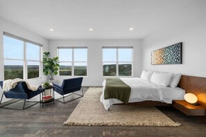Primary suite offering panoramic views of Hill Country. Enjoy the king-size bed, blackout blinds, 65" TV, reading area, walk-in closet, and en suite bathroom. Experience unmatched luxury and comfort.