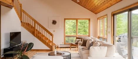 The interior of the home is beautifully designed with bright and airy spaces, including the living room, which contains cathedral ceilings and panoramic mountain views.