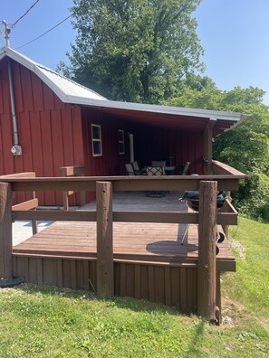 Side view of rear deck with covered seating and charcoal grill.