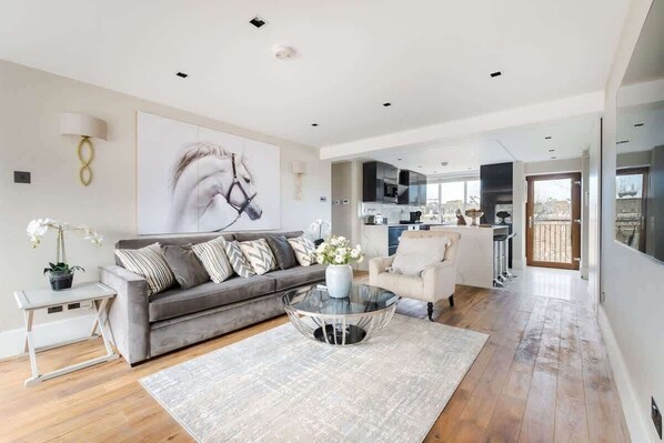 Spacious lounge with 55" TV, A/C & open-plan kitchen for relaxed luxury.