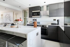 Stylish kitchen with island, stools, washer, dryer, dishwasher & Nespresso.