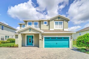 Inviting two-story vacation home with a bright turquoise door and matching garage, perfect for a family getaway.