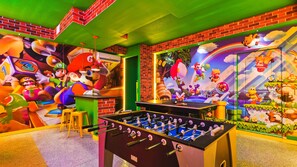 Mario-themed game room with vibrant murals, foosball, and ping-pong for all ages.