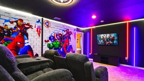 Marvel-themed home theater with neon lights, recliners, and epic superhero murals.