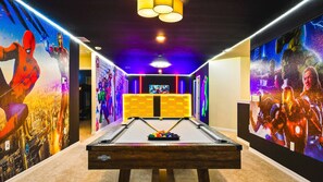 Marvel-themed game room with bold murals and a pool table for heroic hangouts.