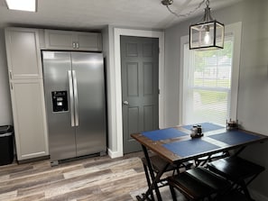 Kitchen area with new stainless refrigerator and dining table for four