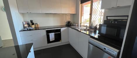 Fully contained kitchen with fridge, microwave, hot plates, oven, dishwasher.