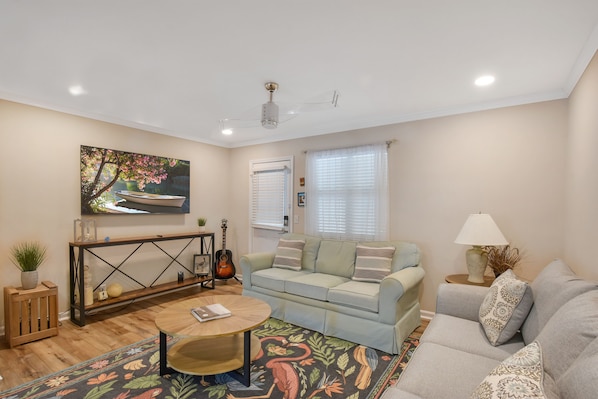 Bright Living Space with Smart TV - This cozy living area at Courtyard Villas E-5 features a large smart TV, plush seating, and playful design touches. Perfect for unwinding after a day at the beach, this St. Simons Island condo is dog friendly and ideal for families or couples.