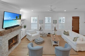 Blue Heron Cottage Living Room – Smart TV, Fireplace & Open Layo - The heart of Blue Heron Cottage—a coastal living room with a mounted Smart TV, shiplap walls, and a decorative fireplace. Gather the crew, start a movie, or just enjoy the clean lines and soft light. It’s laid-back luxury, St. Simons style.