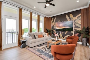 Upscale oasis living room design featuring a 75" smart tv and Queen sofa bed with access to stunning views of Houston skyline.