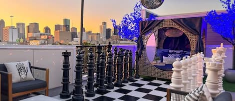 Feel the vibe and take in the Houston skyline on our large outdoor rooftop featuring spacious seating around the warm fire pit, a LIFESIZED chessboard, and a cozy cabana to lay down and relax.