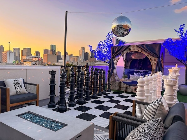 Feel the vibe and take in the Houston skyline on our large outdoor rooftop featuring spacious seating around the warm fire pit, a LIFESIZED chessboard, and a cozy cabana to lay down and relax.