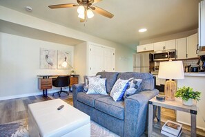 Living room with loveseat. Work desk and chair is in the background.