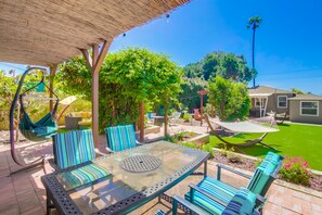 Back patio space with dining table for four, hammocks, shared hot tub, fire pit and propane grill