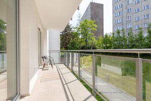 A spacious balcony with glass railings offering a serene view of the surrounding garden and outdoor spaces.