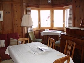 Living room with traditional wooden panels from Swiss Mountain Pine and a big table, bay window, with beautiful view