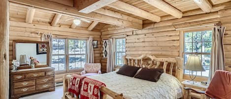 A bedroom in a log cabin with a bed and dresser.