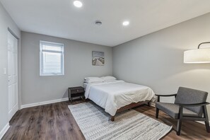 Large, bright room with a comfortable Queen-sized bed, accent chair for relaxing