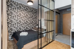 A cozy bedroom with dark accents, a bed, and patterned wallpaper.