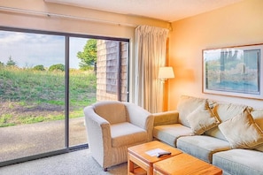 The cozy living room with patio looks out to the green space!