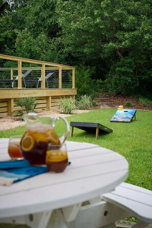 Time to picnic outdoors with a large grassy yard surrounded by trees