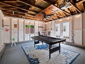 Game night ready! 🎯 This stylish garage hangout features a pool table, mounted TV, bar seating, string lights & a cozy vibe for hours of indoor fun. Perfect for rainy days or evening chill-outs! 🎱📺