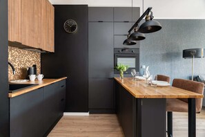 A sleek black-and-wood kitchen paired with a cozy dining area, illuminated by stylish pendant lights.