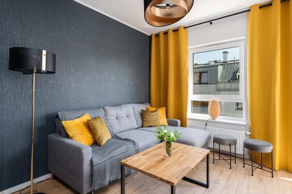 A stylish living room featuring a gray sofa with yellow throw pillows, a coffee table, and modern decor elements.