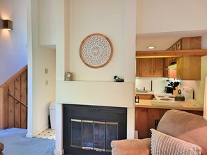 View from living area to kitchen, fireplace and stairway